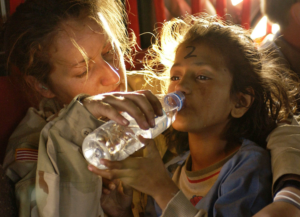 U.S. Army Sergeant Kornelia Rachwal gives a young Pakistani girl a drink of water as they are airlifted from Muzaffarabad to Islamabad, Pakistan, aboard a U.S. Army CH-47 Chinook helicopter on the 19 October 2005.