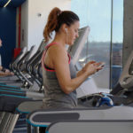 Woman looking at her phone while on a treadmill