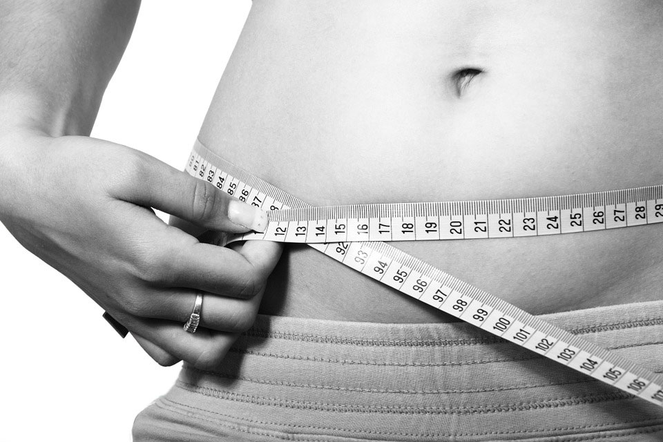 black and white photo of girl measuring stomach with measuring tape