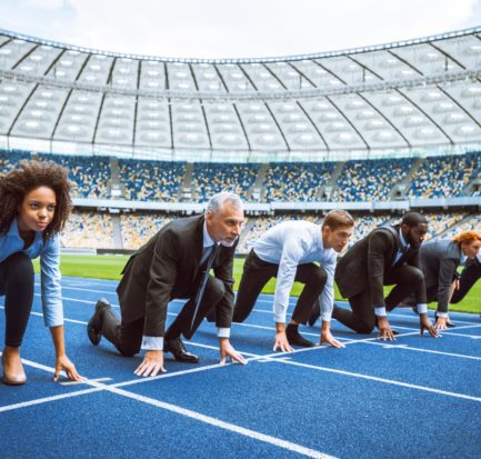 Side view photo of confident multi ethnic business people lined up getting ready for race on modern sport track. Stadium as a background