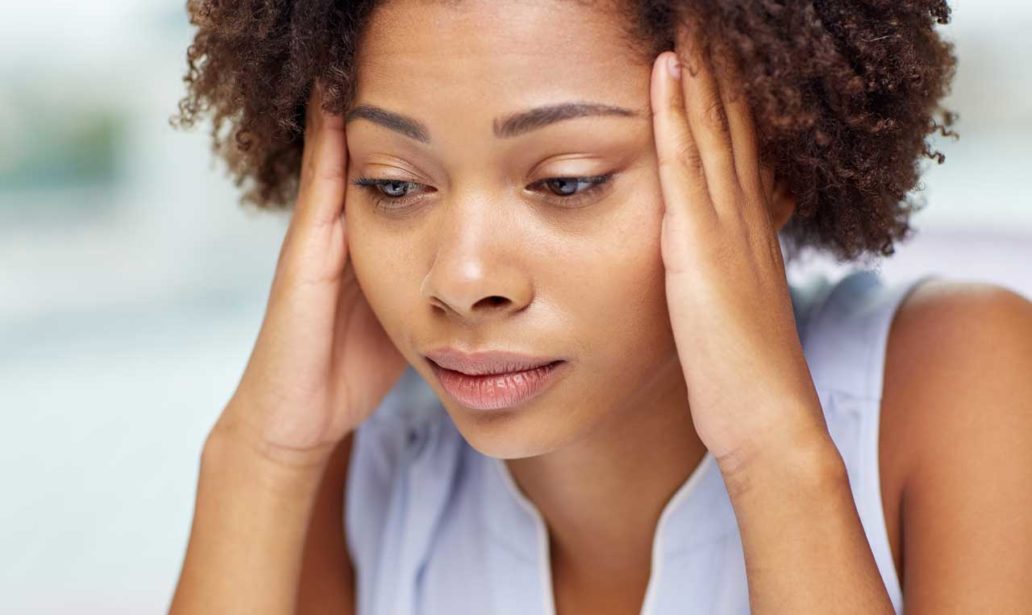 people, emotions, stress and health care concept - unhappy african american young woman touching her head and suffering from headache
