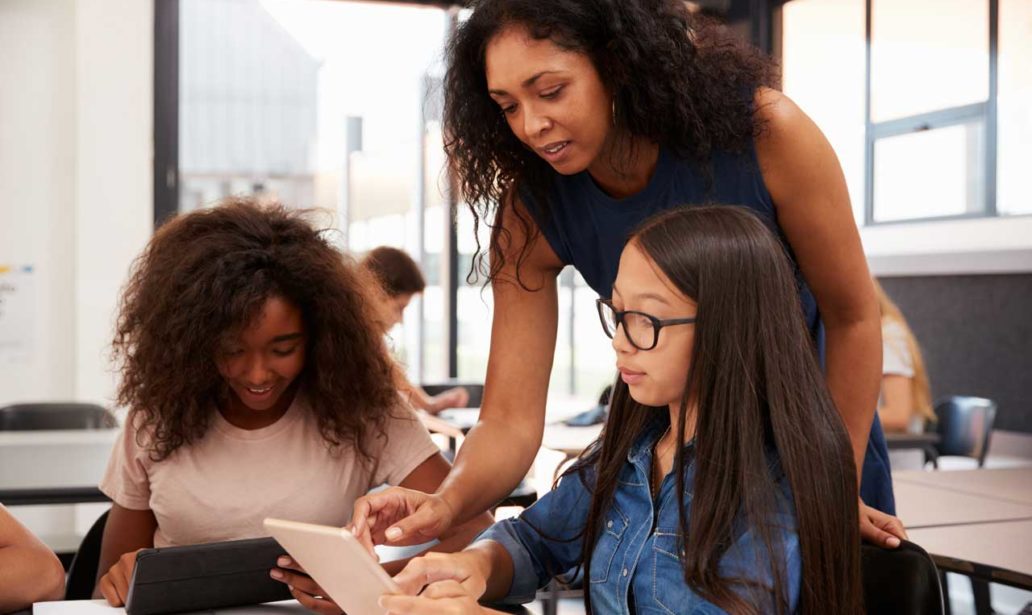 Teacher helping high school students with technology