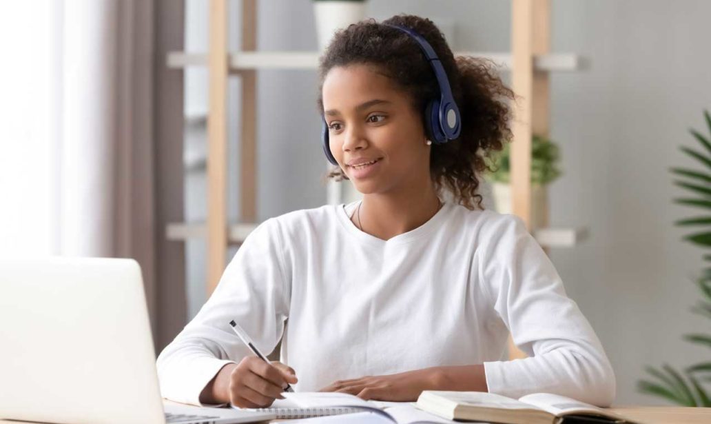 African teen girl wearing headphones study with internet chat skype teacher prepare for exam, black girl school student learning online, watch webinar make notes looking at laptop, distance education