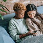 focused lesbian couple with smartphone on sofa