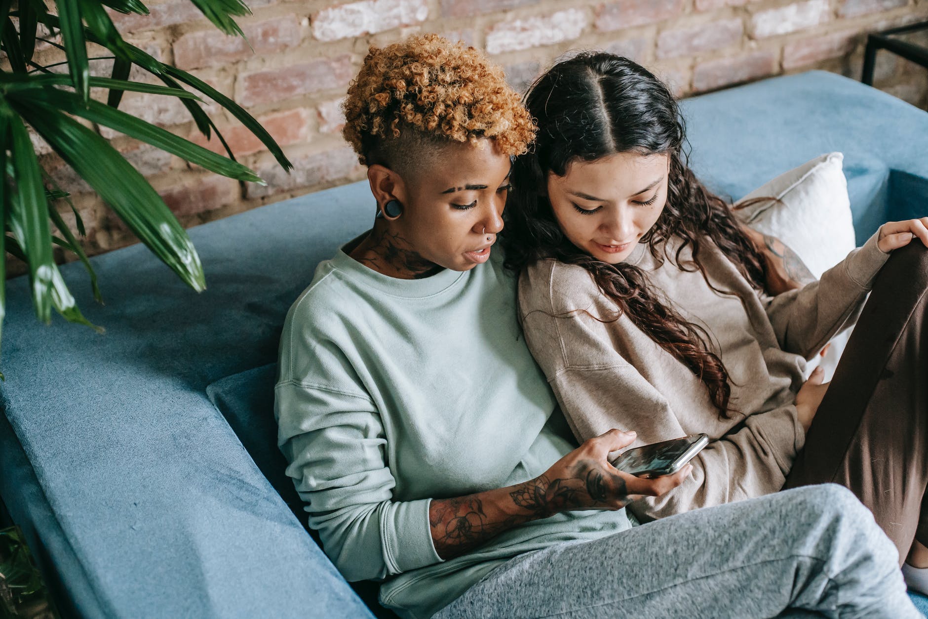 focused lesbian couple with smartphone on sofa