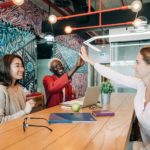 happy diverse female coworkers giving high five after successful deal