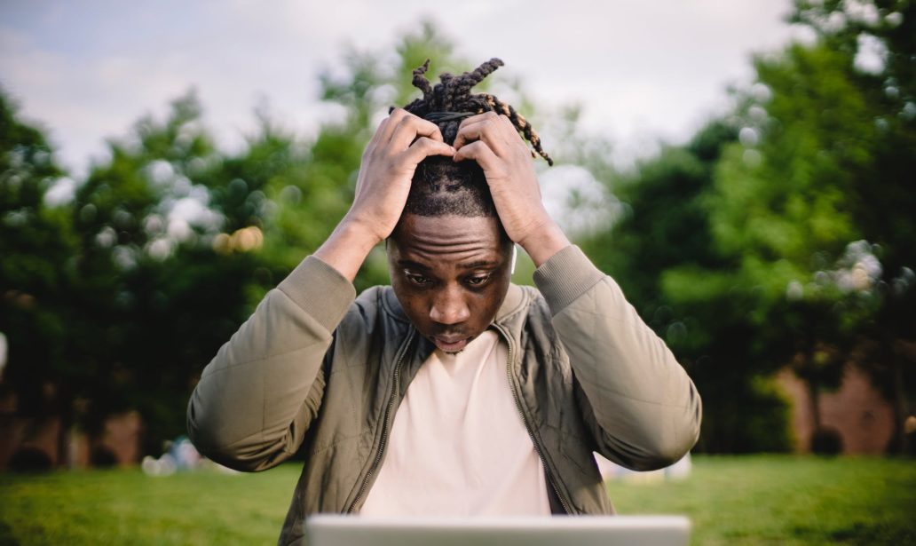 stressed black male entrepreneur working on laptop in park