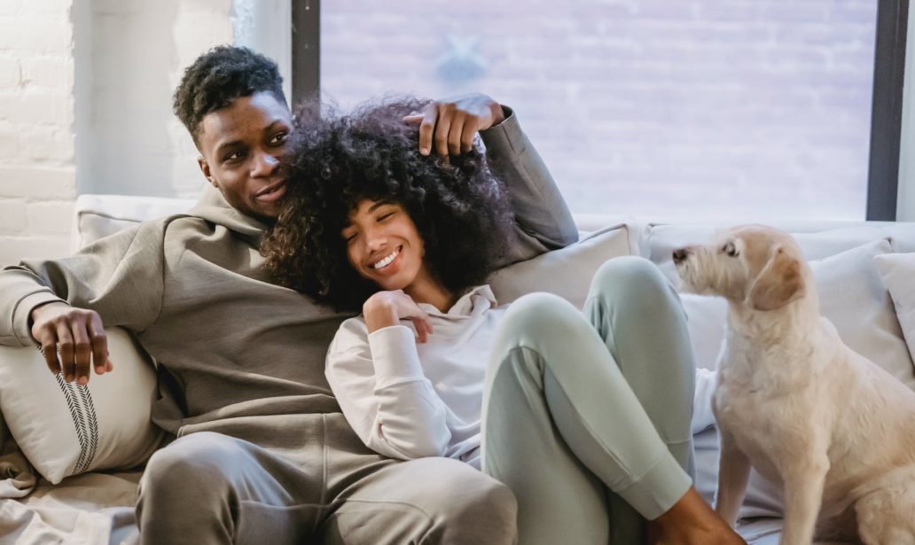 romantic black couple chilling on couch with dog