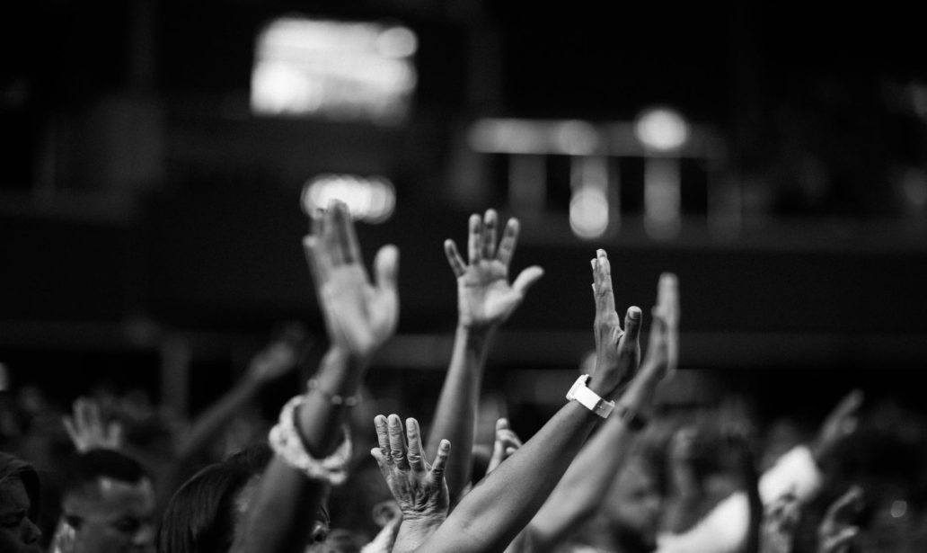grayscale photography of people raising hands