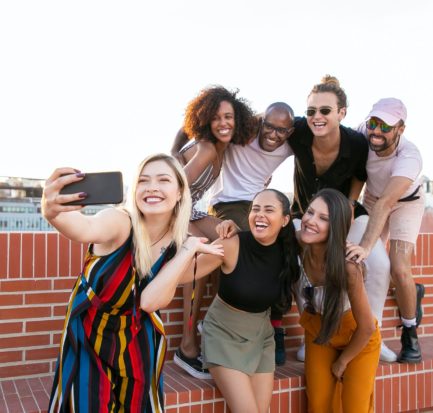 excited young diverse men and women taking selfie on rooftop