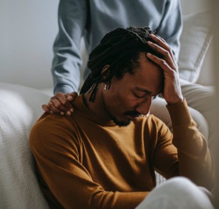 sorrowful black man touching head in dismay near supporting wife