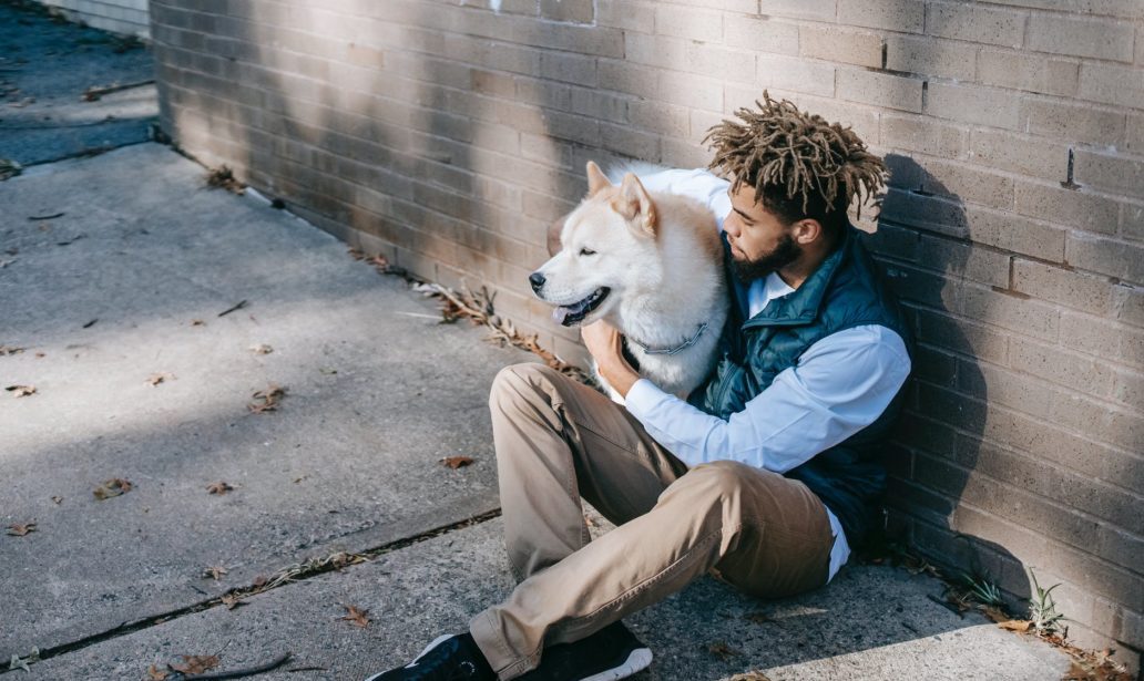 young man sitting with white dog