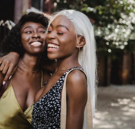 two women friends smiling and hugging each other