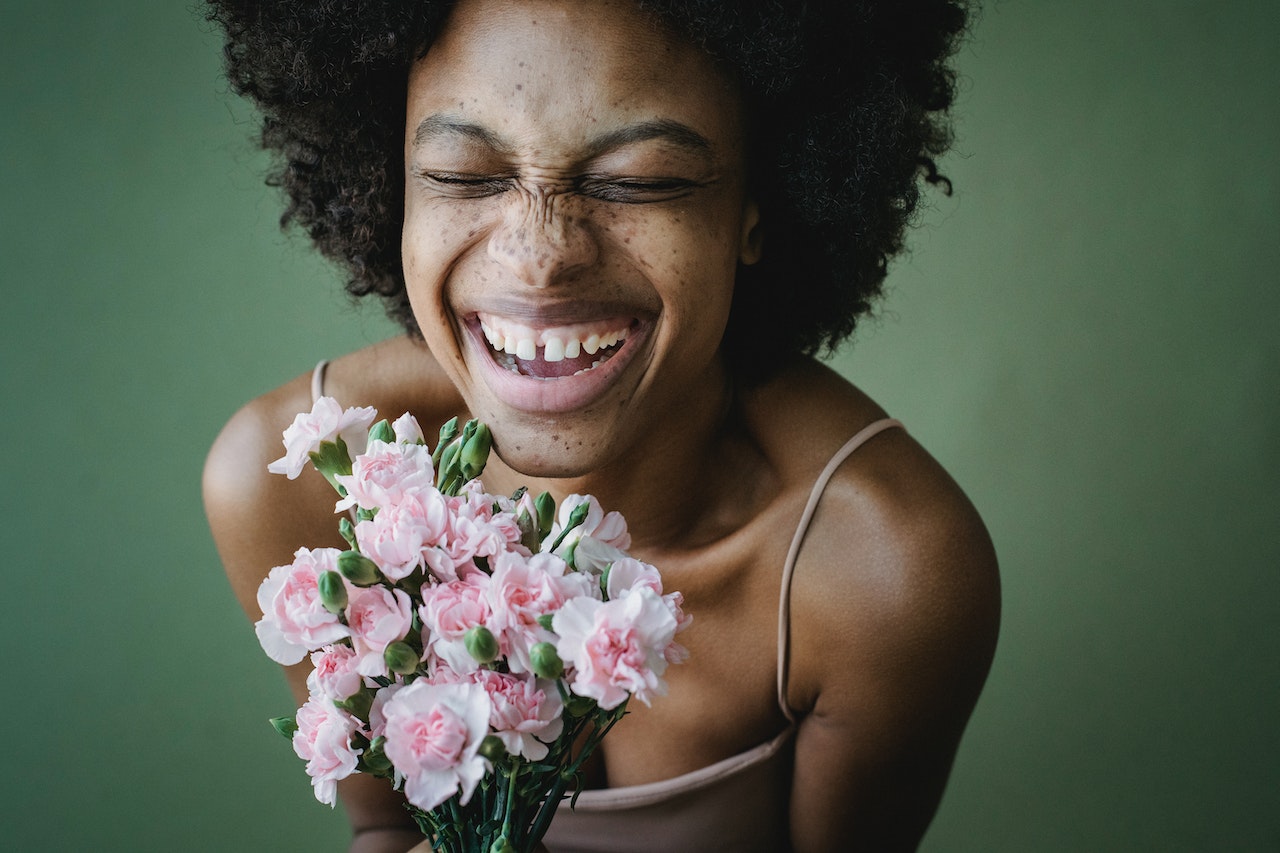 woman smiling and holding a bunch of flowers