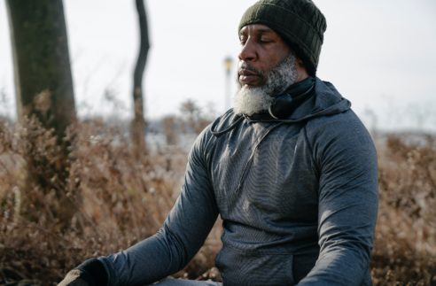 thoughtful black man in activewear meditating in autom park