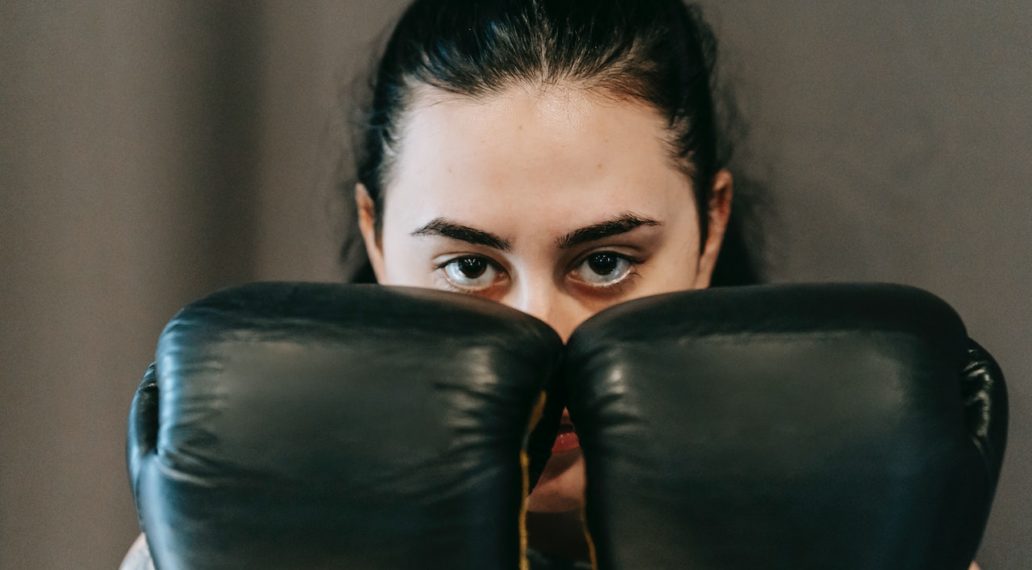 serious young sportswoman standing in boxing defensive stance