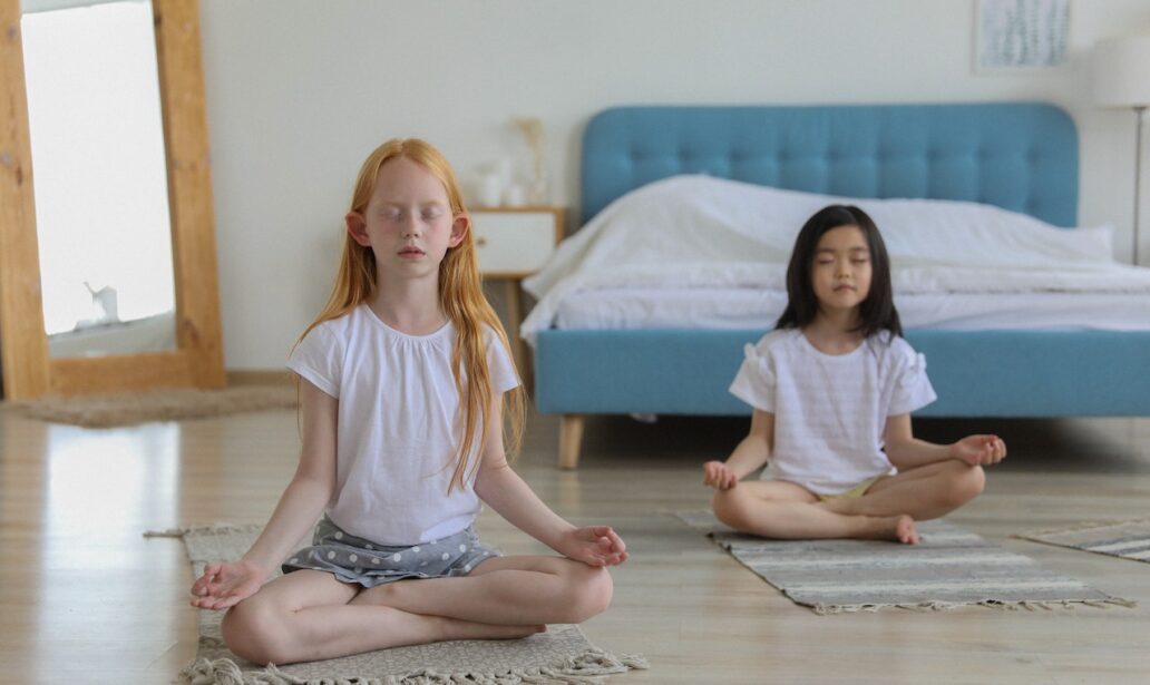 girls with reddish and black hair meditating in room