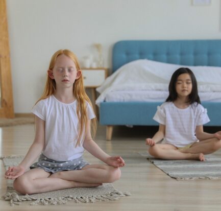 girls with reddish and black hair meditating in room