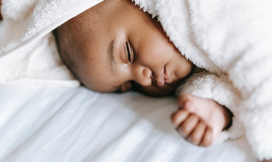 sleeping newborn black baby lying on a bed