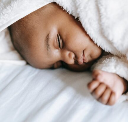 sleeping newborn black baby lying on a bed
