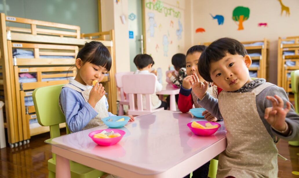 three toddlers eating on white table