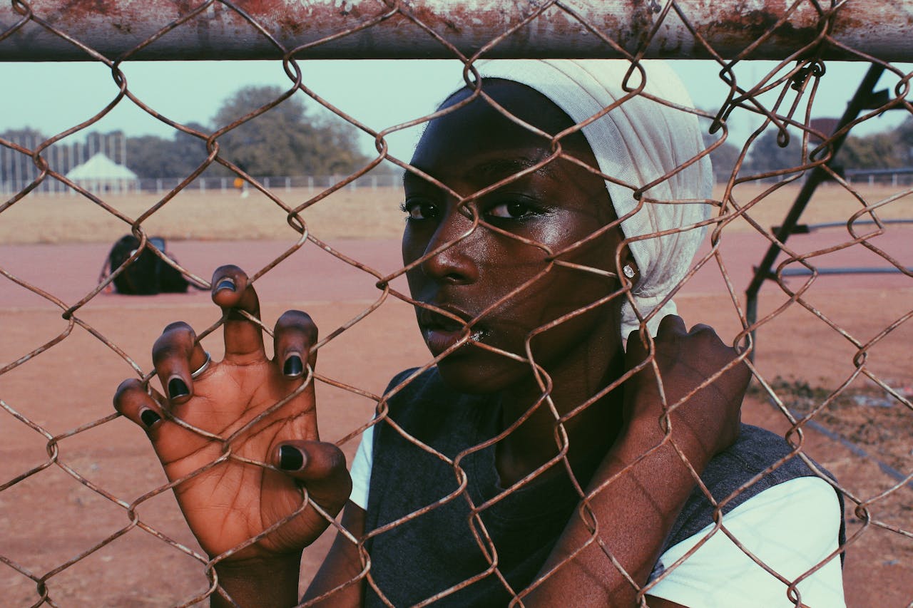 black woman with headscarf behind fence
