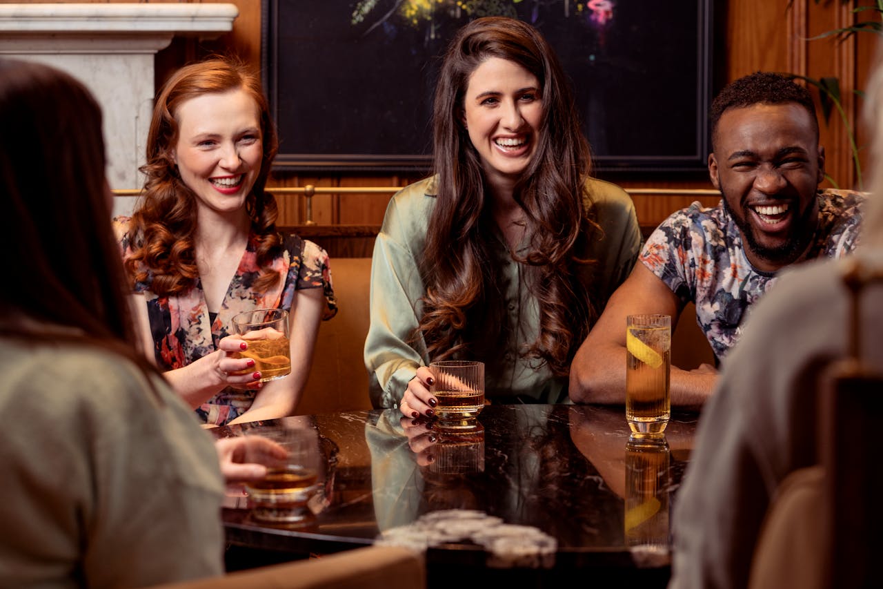 cheerful friends sitting with drinks at a table