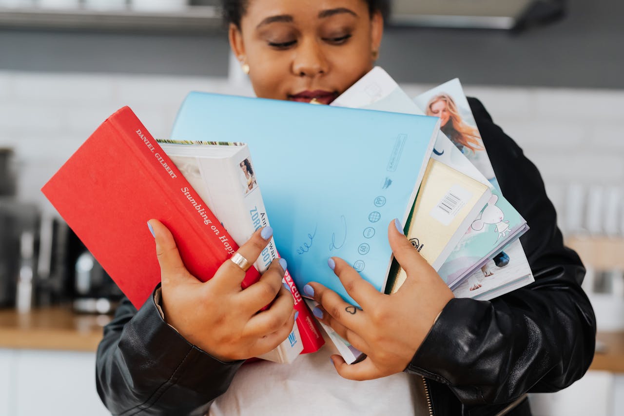 woman in black leather jacket holding six books
