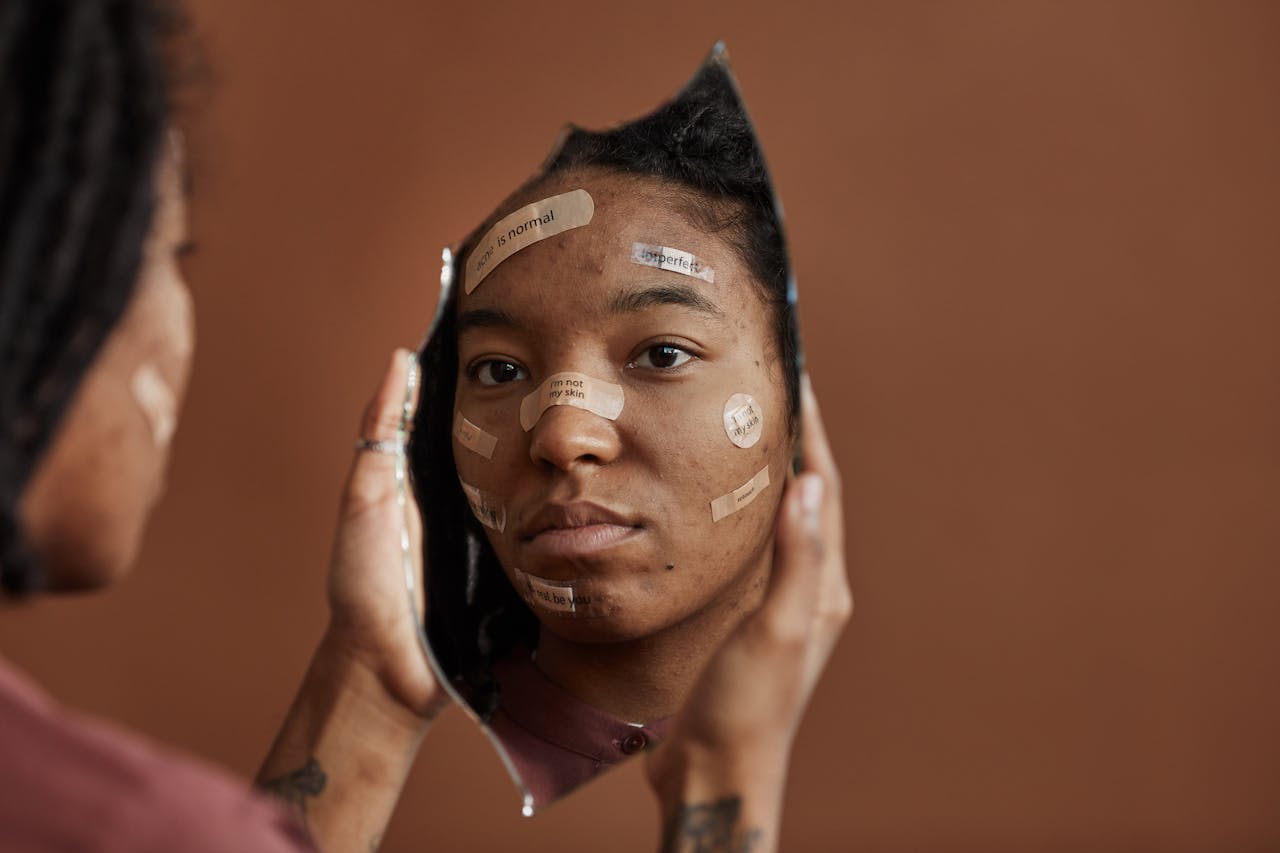 a sad woman looking at herself on a broken mirror she is holding