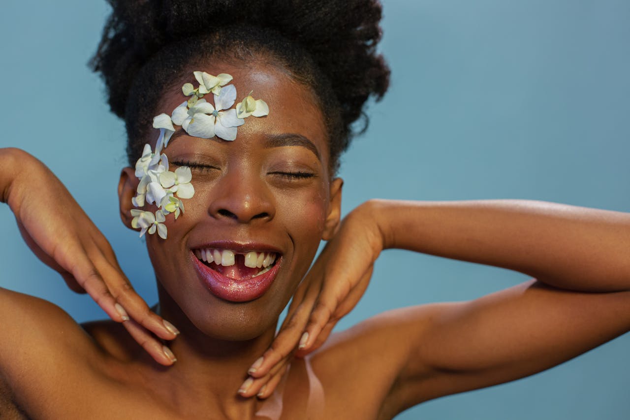 joyful young ethinic lady smiling with closed eyes in blue studio