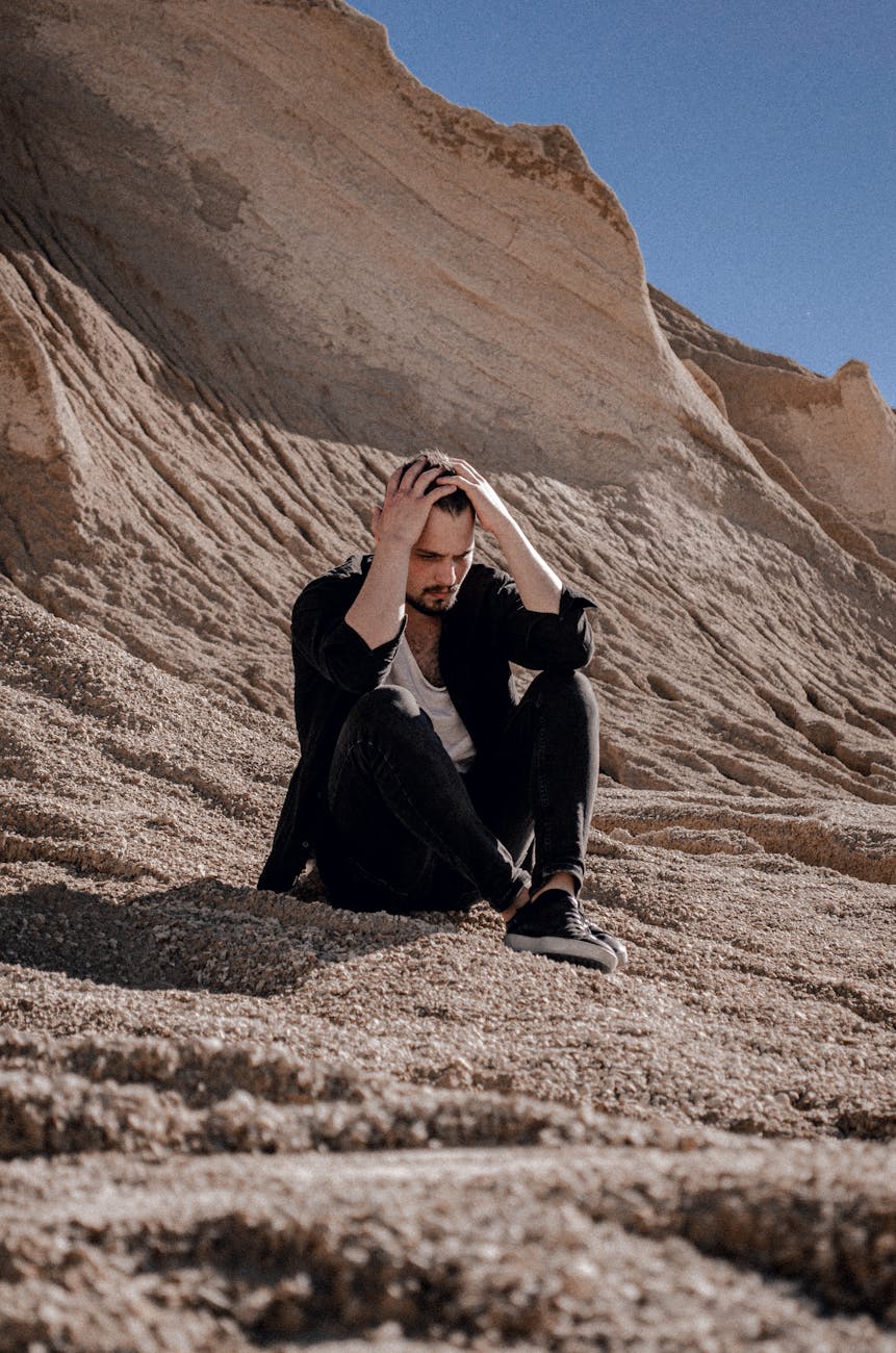 man sitting on beach near cliff