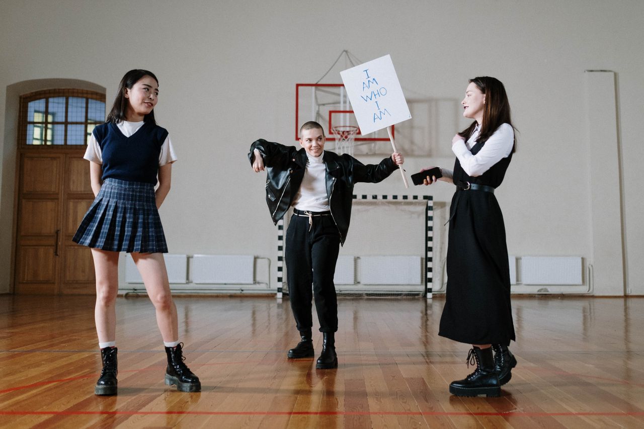 women looking at each other. one is carrying a sign that says "I am what I am"