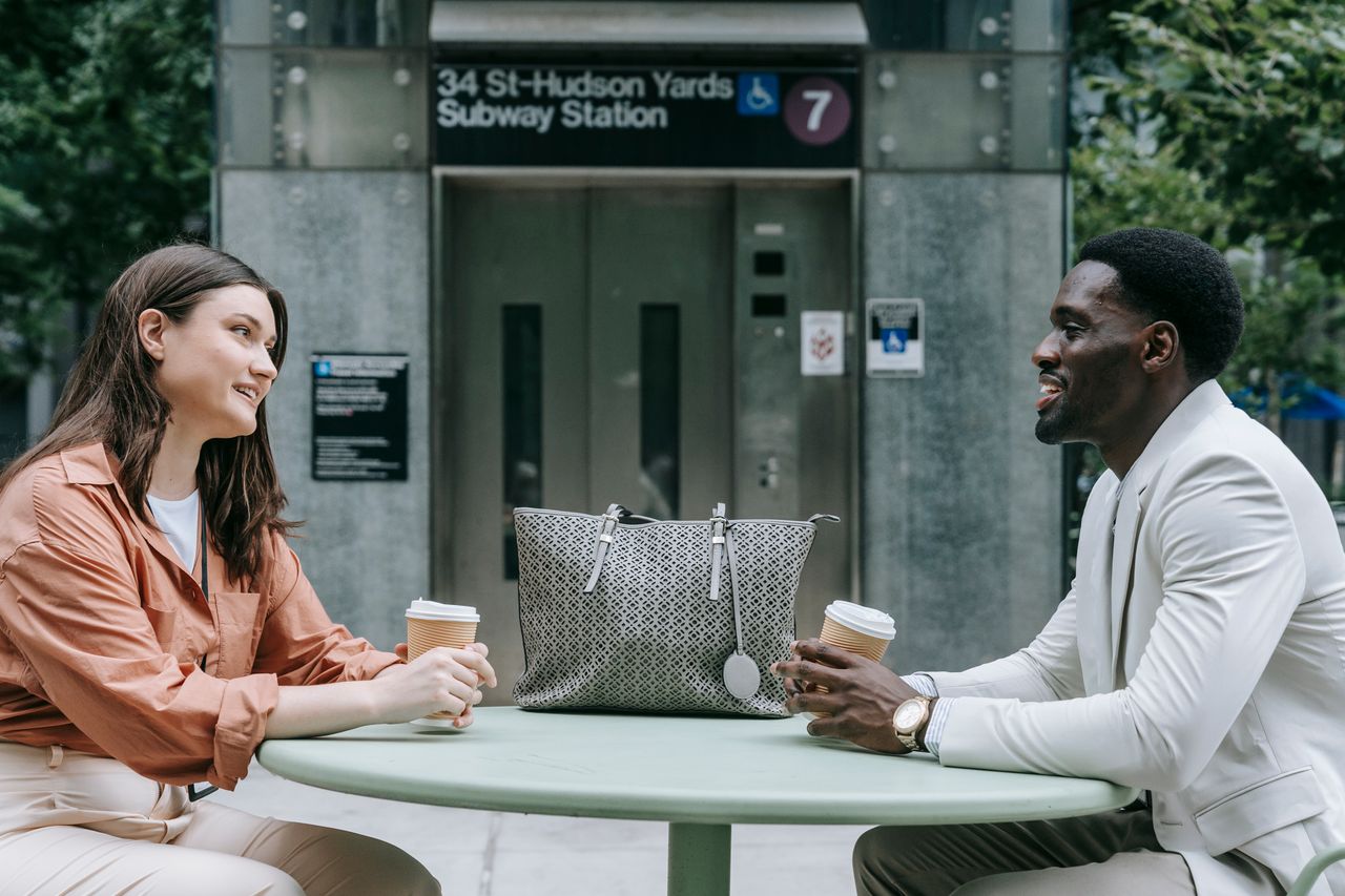 Two people chatting over coffee outside 34 St-Hudson Yards Subway Station in NYC.
